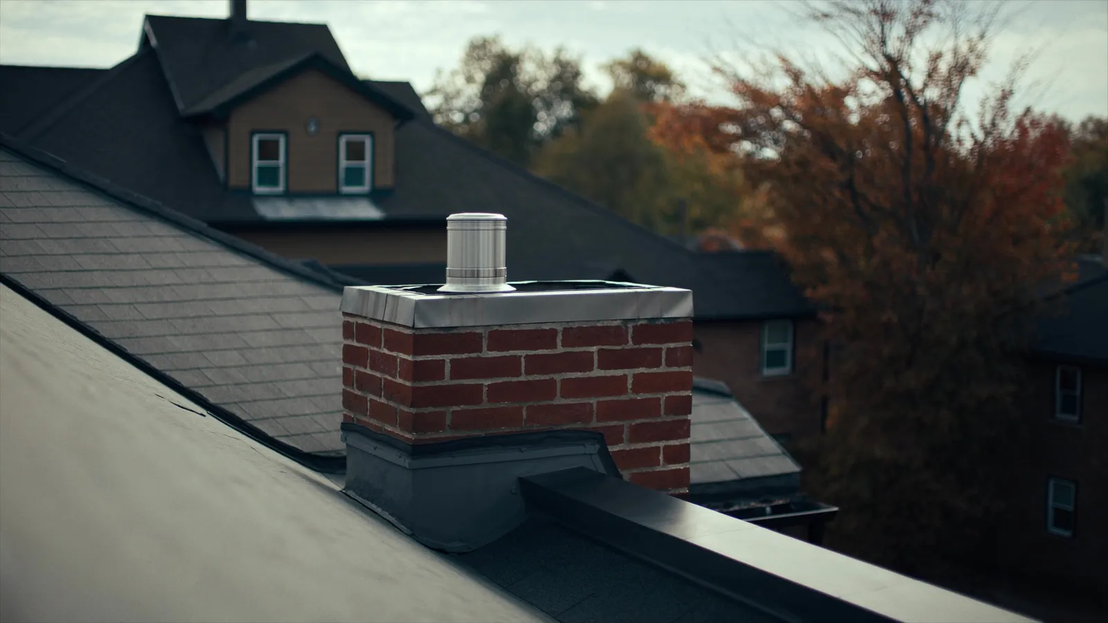 A brick chimney with new flashing and a stainless cap on a shingle roof