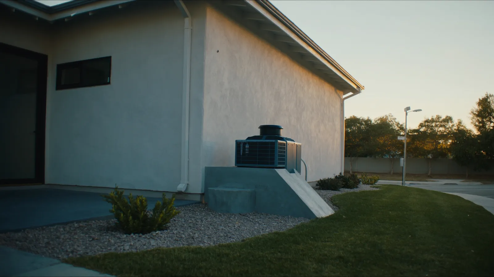 A new high-efficiency HVAC condenser beside an upscale stucco home at golden hour