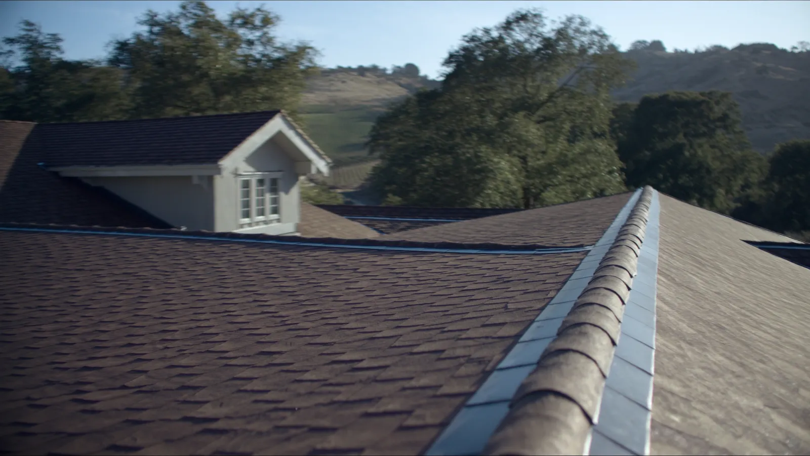 A finished composition shingle roof on a craftsman home with vineyard hills behind it