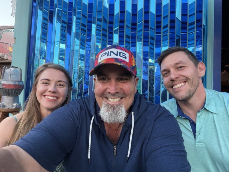 Three people together in a venue lit blue.