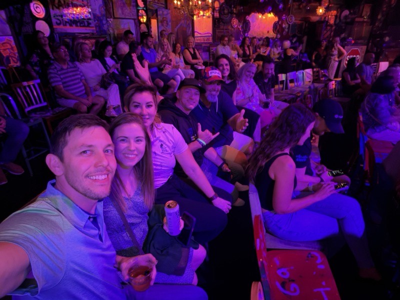 A group seated together in a dimly lit venue with stage lighting.